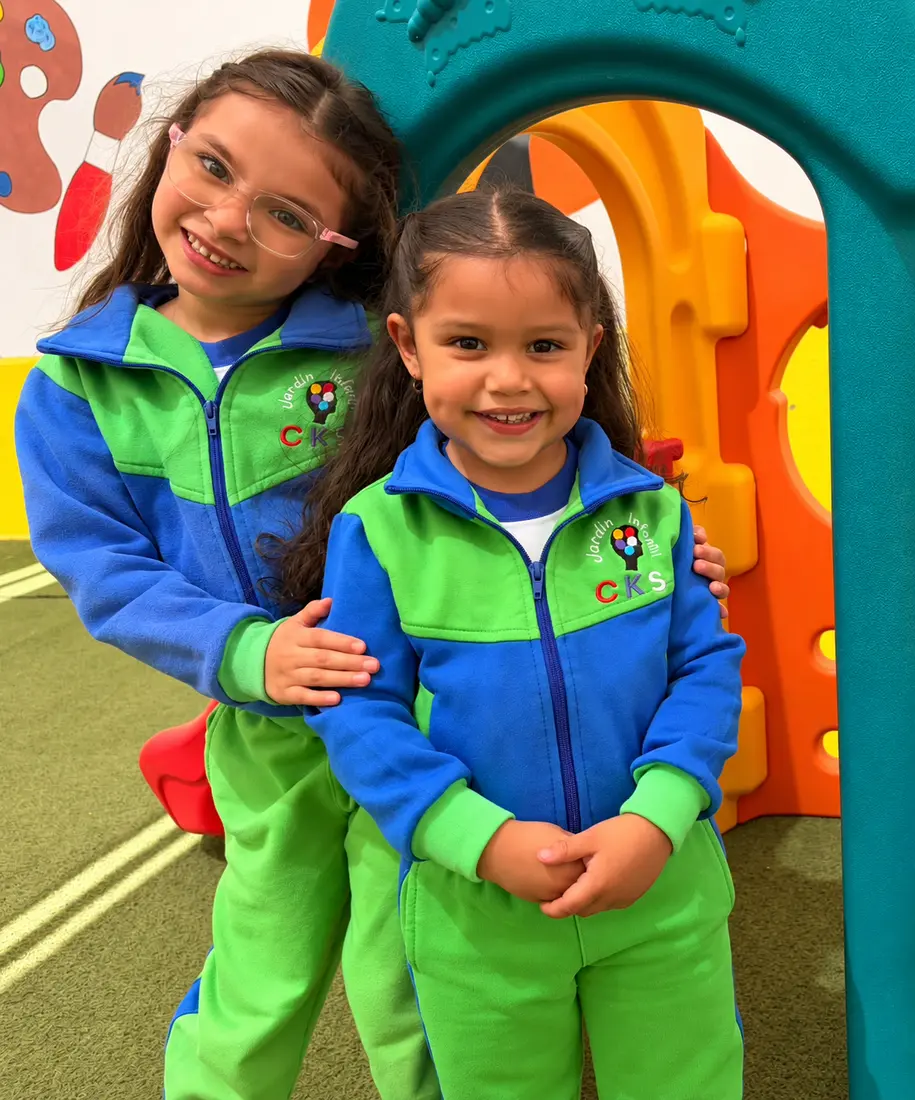 Dos niñas del Jardín Infantil CKS compartiendo una sonrisa en los juegos del patio