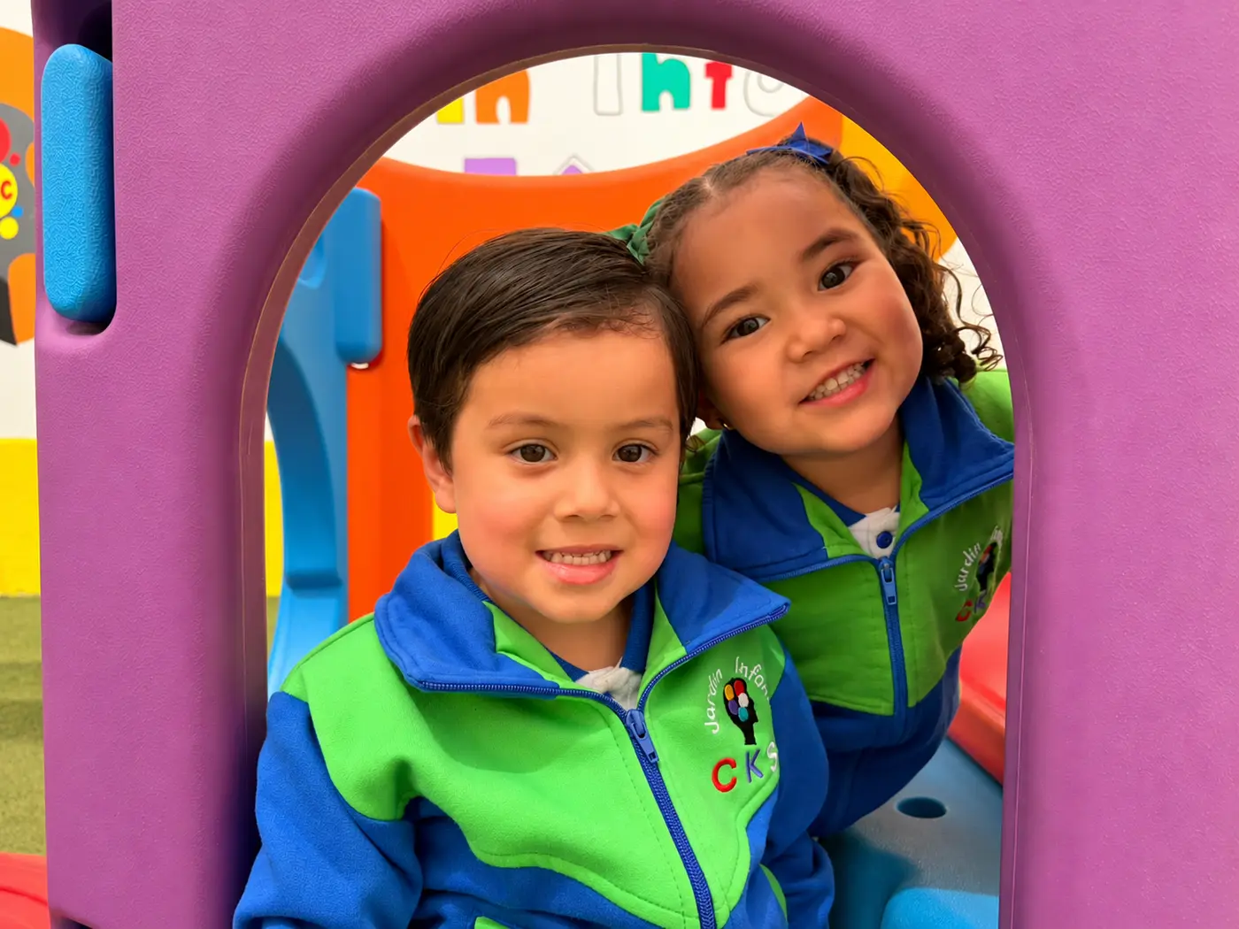 Niño y niña del Jardín Infantil CKS sonriendo juntos en los juegos