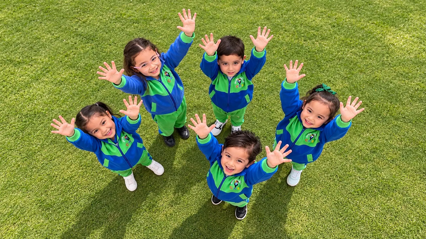 Niños y niñas del Jardín Infantil CKS saludando en el patio